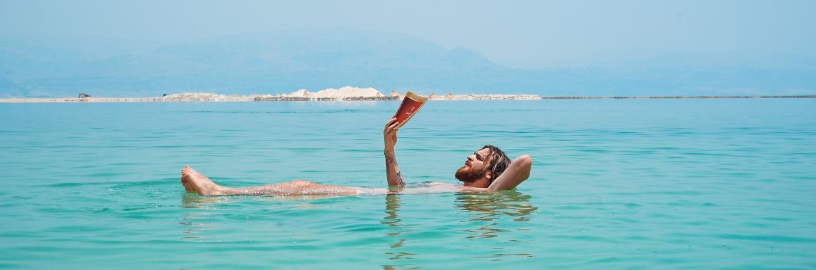 Homme se baignant dans la mer avec un livre à la main